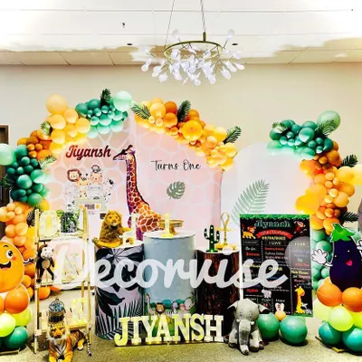This full stage setup for Jiyansh's "Wild One" birthday is packed with jungle fun. It features character cutouts of lions and elephants, giraffe-print backdrops, and balloon garlands in safari-inspired colors like orange, green, and gold.