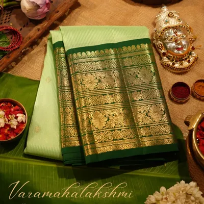 A perfect offering for Varamahalakshmi, this light green Kanjivaram with a dark green peacock border is laid out with traditional puja items.