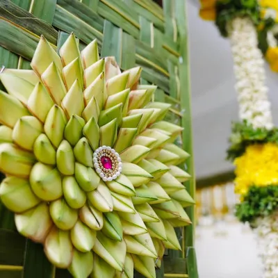 A close-up showcasing the intricate detail of our eco-friendly decorations. This beautiful medallion is handcrafted from fresh coconut leaves, a traditional art form that adds a unique and sustainable touch to any event.