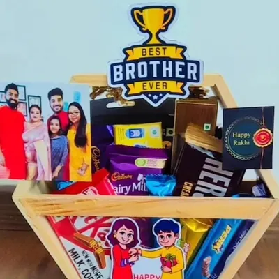 Show him he's the 'Best Brother Ever' with this personalized Rakhi hamper. It includes a custom photo, a variety of his favorite chocolates like Dairy Milk and Hershey's, and a Happy Rakhi card, all packed in a hexagonal wooden crate.