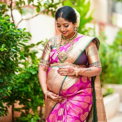 A beautiful outdoor portrait of the mother-to-be on her baby shower day. Dressed in a stunning pink and gold silk saree, she radiates joy and anticipation.