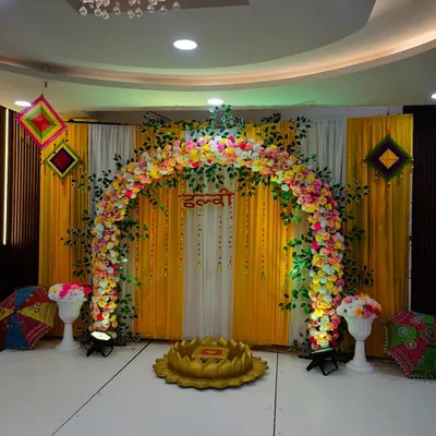 This is my signature Haldi ceremony stage. The full floral arch, bright yellow and white drapes, and traditional props like the lotus-shaped seat create a classic and joyful setting.