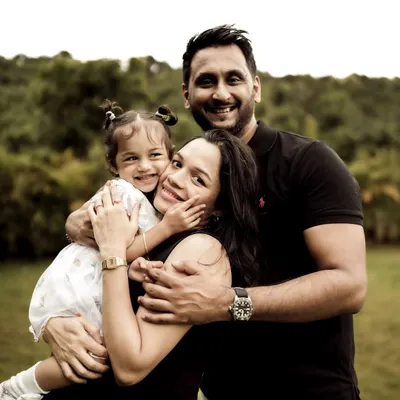 The perfect family hug. This portrait captures the joy and love of a family of three, soon to be four. The daughter's happy face nestled between her parents is a priceless memory.