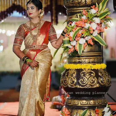 A bride posing next to a large, ornate pillar, a decorative element that adds grandeur to the entrance or stage area.