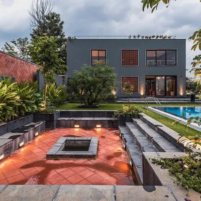 A complete view of 'The Grey Grotto' estate, showing the relationship between the main house, the sunken fire pit lounge, the swimming pool, and the surrounding landscape. This project won a Bronze award at the ADC International Design Awards 2023.