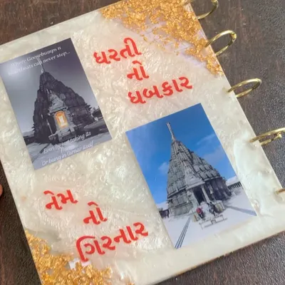 A custom resin book cover made for a religious book about Girnar. It features photos and text in Gujarati, with a beautiful white and gold design.