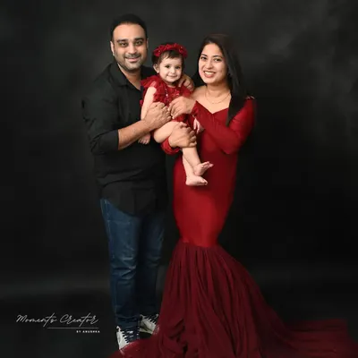 A classic family portrait against a dark, moody backdrop. The coordinated red and black outfits create a striking and elegant look, perfect for a timeless piece of wall art.