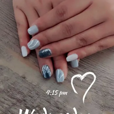 A chic set in shades of grey and white, featuring a bold, dark blue glitter accent nail and subtle white swirl art.