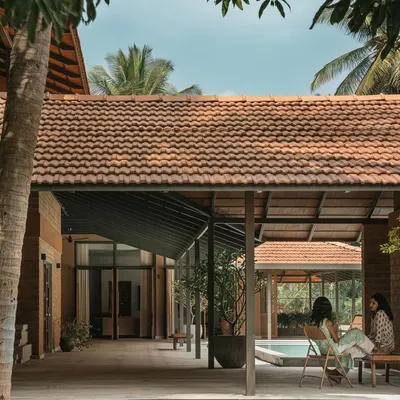 An expansive view of Villa Maati, a peaceful sanctuary we designed within a coconut farm. The open-air corridors and seating areas are positioned to offer relaxing views of the central pool and surrounding landscape.