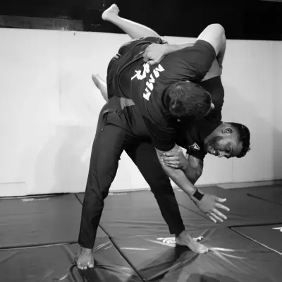 A powerful takedown in action. This black and white shot captures the moment a fighter executes a throw, demonstrating a key skill in wrestling and judo for MMA.