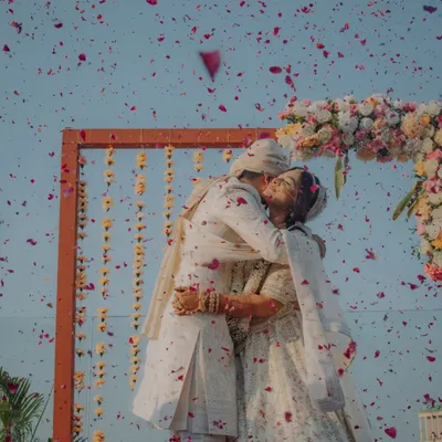 A shower of petals for a lifetime of happiness. This Varmala moment, captured against the sky, is one of our favorite shots to take, symbolizing the community's blessing on the couple.