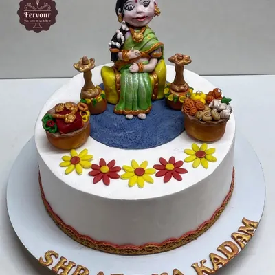 A traditional Godh Bharai (baby shower) cake. This design features a hand-sculpted fondant figure of an expecting mother in traditional attire, surrounded by auspicious items.