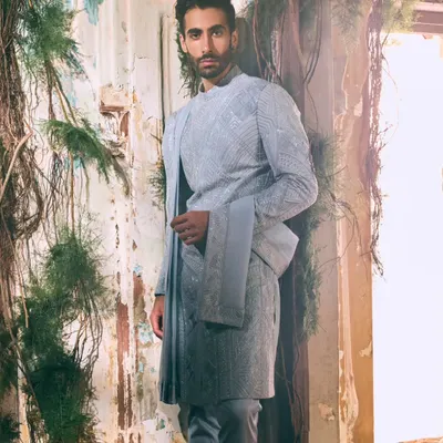 This textured ensemble in a serene, cool tone exemplifies quiet sophistication. The tailored silhouette and intricate fabric offer a modern take on traditional menswear, perfect for a groom or wedding guest who prefers understated elegance.