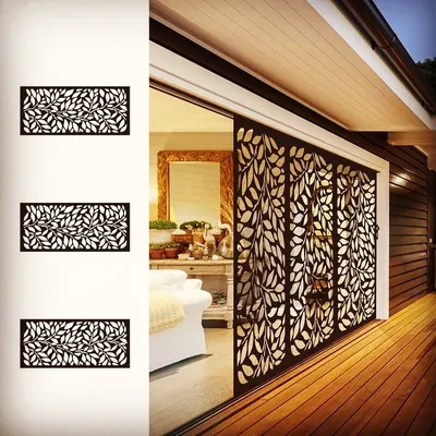 This laser-cut metal screen is a beautiful and functional solution for privacy. It separates the outdoor and indoor areas while allowing light to pass through, casting intricate, leaf-patterned shadows.