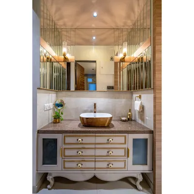 An opulent and functional vanity area. We designed this custom piece with classic carved legs, ornate drawer knobs, and a beautifully lit mirror to create a luxurious space for daily rituals.