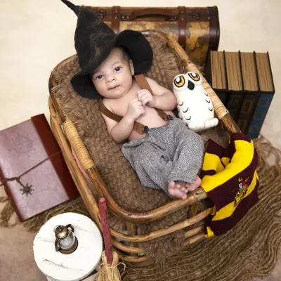 An alternate angle from the Harry Potter themed shoot, this time with the baby awake and looking at the camera. This shot captures the detailed props like the sorting hat, suspenders, and a plush owl.