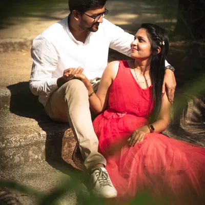 A classic romantic pose from a post-wedding shoot in a park. The couple is sitting on stone steps, lost in each other's eyes, with soft natural light filtering through the trees.