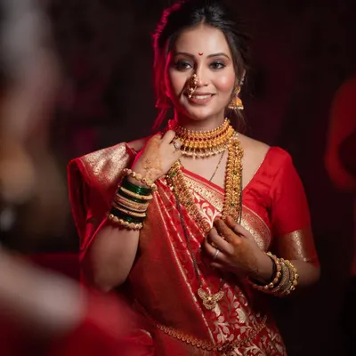 A stunning bridal portrait, with the bride looking in a mirror, her face illuminated by soft light, highlighting her beautiful makeup and jewelry.