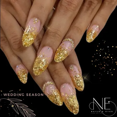 This is the ultimate glamorous look for the wedding season. It features a heavy cascade of chunky gold glitter over a sheer nude base on long, almond-shaped nails.