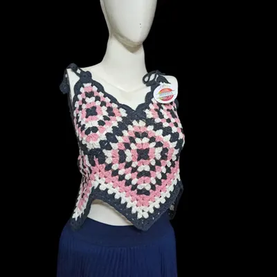This handkerchief-style top is made from a large granny square, creating a unique pointed hem. The color combination of pink, white, and charcoal grey makes it a modern and eye-catching piece.