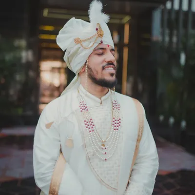 A classic portrait of a Maharashtrian groom on his wedding day. With his eyes closed and a peaceful smile, this shot captures a moment of quiet anticipation before the ceremony begins.