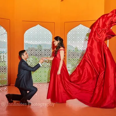 A dramatic proposal scene enhanced by a flowing red gown, captured in our studio. We expertly manage fabric to create dynamic, wind-swept effects for a high-fashion look.