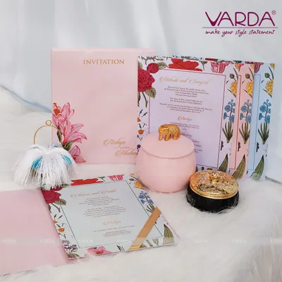 This beautiful invitation suite features a soft pink folder and cards with a vibrant floral border. It's paired with charming ceramic jars, one in pink with an elephant lid, creating a whimsical and elegant gift.