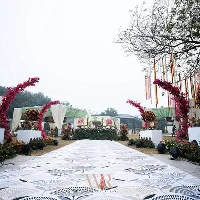 The entrance to a bohemian dream. I used a printed carpet to create a unique aisle, leading to arches adorned with vibrant pink bougainvillea, creating a joyful and spirited welcome for this day wedding.
