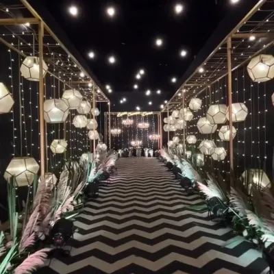 I designed this grand entrance for a corporate annual event, creating a memorable walk-in experience. The setup features a custom golden framework, geometric lanterns, and dramatic fairy lights over a bold chevron-patterned carpet to set a sophisticated and modern tone.