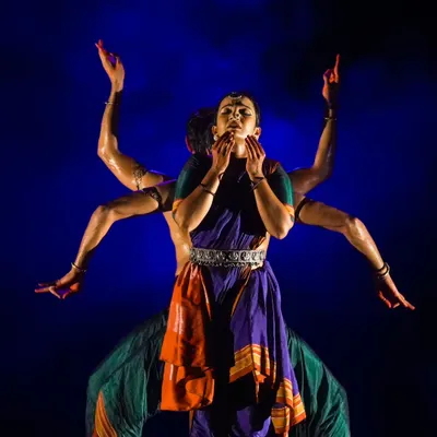 A powerful visual from 'Nagamandala' where multiple bodies create a single, divine form. This kind of group choreography requires perfect synchronization and a deep understanding of spatial dynamics to achieve a striking visual effect.