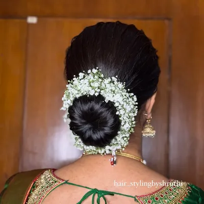 A classic, neat bridal bun completely encircled with a gajra of fresh baby's breath. This is a timeless and elegant updo that pairs perfectly with a traditional silk saree for any wedding function.