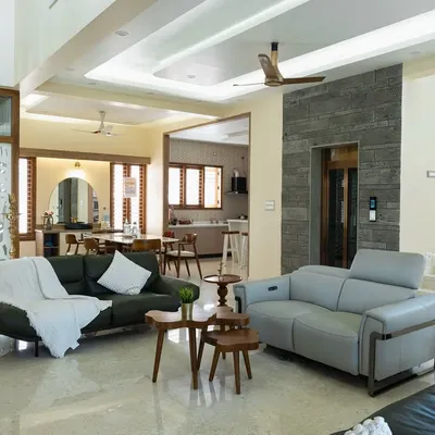 An expansive open-plan villa interior where the living and dining areas flow seamlessly. The high ceiling, marble flooring, and mix of modern sofas create a feeling of spacious, airy luxury.