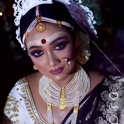A dramatic Bengali bridal look featuring a pearl rani haar, traditional makeup, and the white 'mukut' headpiece.