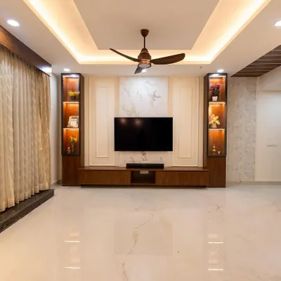 This living room features a sophisticated TV wall with a marble-finish panel and dark wood accents. The vertical display cabinets are backlit to highlight decor, creating a luxurious and balanced focal point.