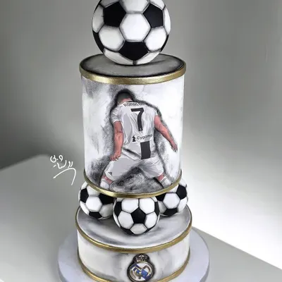 A magnificent three-tiered football cake for a true Cristiano Ronaldo fan. This cake features a hand-painted portrait, the Real Madrid logo, and realistic footballs, making it a champion's choice.