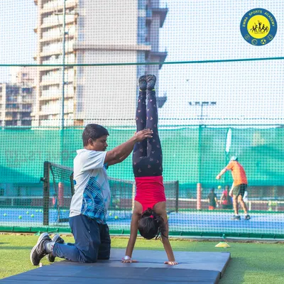 One of our junior gymnasts masters a handstand with the help of a coach. I ensure every child receives the support they need to build strength and fearlessness.