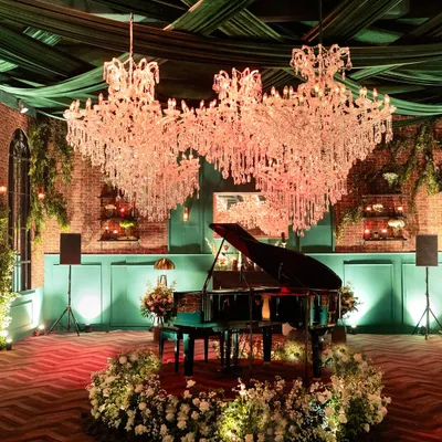 For this contemporary reception in a glass house, I took inspiration from vintage London lofts. The design featured a grand piano as a centerpiece under magnificent crystal chandeliers, with exposed brick walls and lush florals creating a warm, sophisticated, and soulful atmosphere.