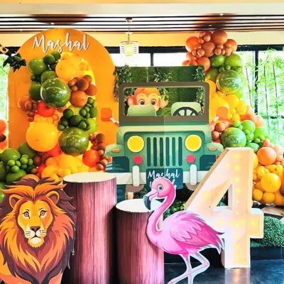 A full view of our jungle safari decor, showcasing the large light-up number '4', a friendly flamingo, and a mighty lion standing guard. The setup is brought to life with a custom jeep photo booth and a backdrop personalized with the birthday boy's name, Mashal.
