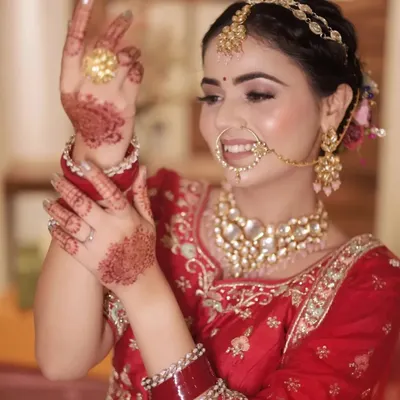 A beautiful, smiling bridal portrait capturing the bride's happiness and intricate details, from her mehendi to her stunning jewelry.