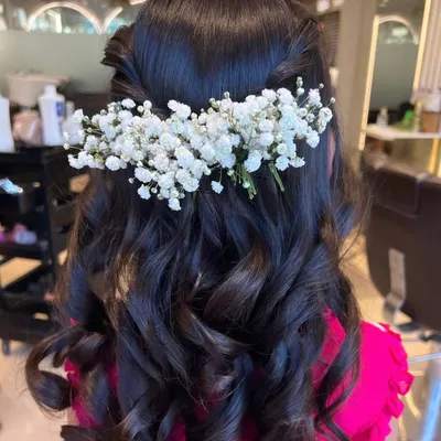 A romantic half-up, half-down hairstyle perfect for any special occasion. The soft curls are adorned with delicate baby's breath, adding a touch of natural elegance.