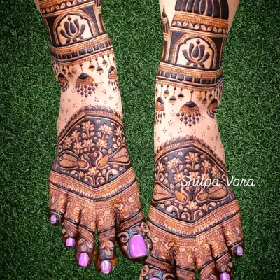 A stunningly detailed bridal foot design, featuring architectural domes, hanging 'jhumka' earrings, and delicate peacock motifs.