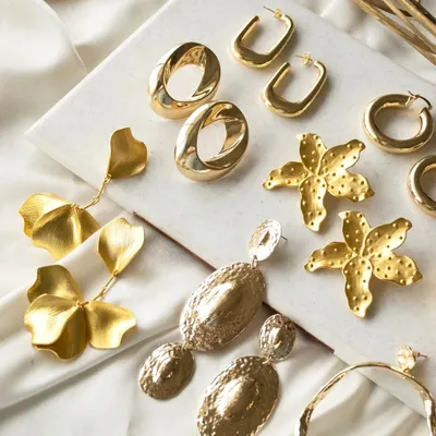 Make a statement without saying a word. This flat lay showcases some of my favorite bold, gold earrings, including spiral groovy ovals, floral drops, and abstract hoops.