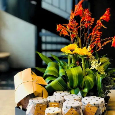 This custom hamper is a great example of my collaborative process. It combines jars of homemade preserves and a beautifully wrapped cake with a vibrant floral arrangement, all nestled in a sleek tray for a client's special occasion.