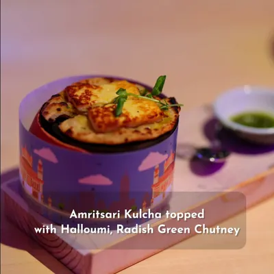 A modern interpretation of a Punjabi classic. This Amritsari Kulcha is topped with grilled halloumi cheese and served with a side of radish green chutney, all presented in a stylish, custom-branded container.