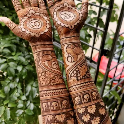 This engagement mehendi was designed to tell a story, with the couple's initials and wedding rings in mandalas on the palm. The arms feature elegant peacock and swan motifs, symbolizing love and partnership.