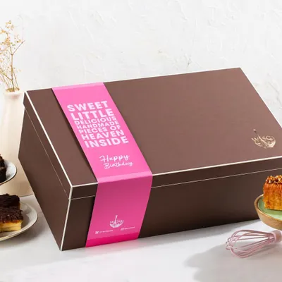 Taking gifting to the next level with our signature gift hampers. This large, elegant brown box is sealed with a custom "Happy Birthday" sleeve, promising "sweet little delicious handmade pieces of heaven inside".