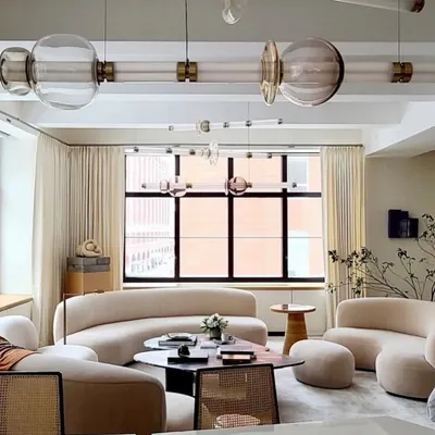 A multi-tiered Luna installation spans a sophisticated living room, with its horizontal elements drawing the eye across the space. The clear and tinted glass pieces interact with the natural light from the large window, showcasing the fixture's adaptability and grandeur.