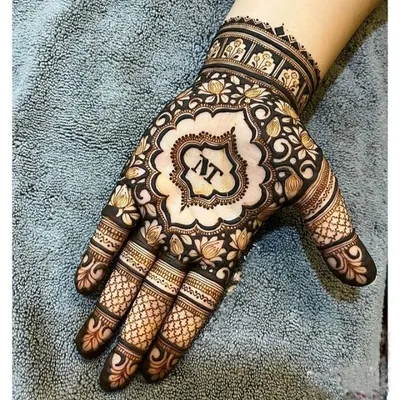 A beautiful way to personalize your mehndi. This design features the couple's initials 'NT' in a stylish font at the center of the palm, surrounded by a floral mandala.