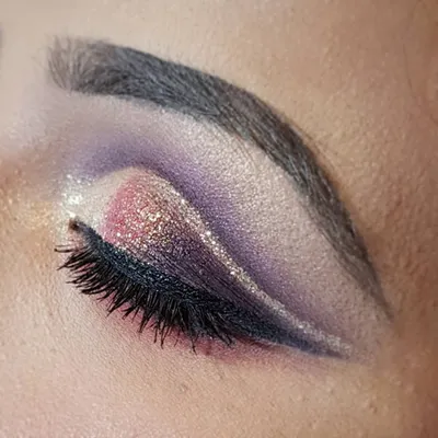 A dramatic cut crease can completely transform your look. Here, I created a sharp crease with a blend of purple and pink tones, adding a line of silver glitter for that extra pop. This is for the client who loves to be bold.
