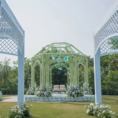 A modern Anand Karaj ceremony in Dehradun, featuring a mint green gazebo-style mandap. The design is clean and contemporary, with a backdrop of the mountains.